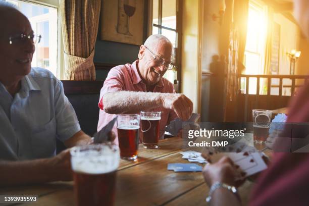 バーで一緒に座ってカードゲームをしたり、絆を深めたり、パブでブリッジのゲームを楽しんでいる先輩の友達のグループ - bridge card game ストックフォトと画像