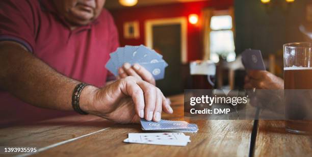 unknown senior man sitting with friends and playing card games in a bar, bonding, senior friends enjoying a game of bridge in a pub - bridge card game stock pictures, royalty-free photos & images