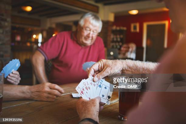 unknown senior man sitting with friends and playing card games in a bar, bonding, senior friends enjoying a game of bridge in a pub - bridge card game stock pictures, royalty-free photos & images