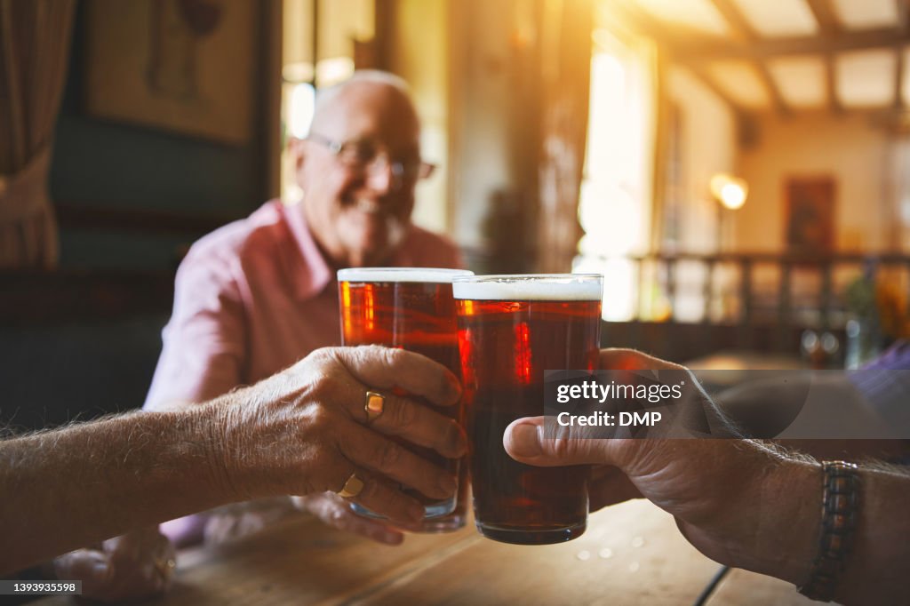 Grupo de hombres mayores desconocidos sentados juntos y brindando con cerveza en un bar, uniéndose, amigos mayores disfrutando de una pinta de cerveza en un pub, vítores