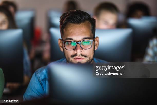 male student learning a lecture over desktop pc at computer lab. - computer lab stock pictures, royalty-free photos & images