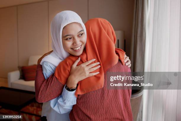 young muslim woman embracing family visit - indonesia family stock pictures, royalty-free photos & images