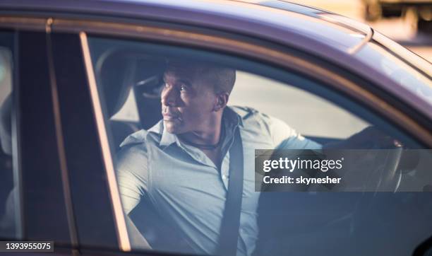 mid adult black businessman driving a car in reverse. - reversing stock pictures, royalty-free photos & images