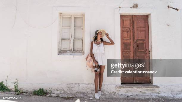 smiling asian woman leaning back on a wall in old town volimes in zakynthos greece - grekiska övärlden bildbanksfoton och bilder