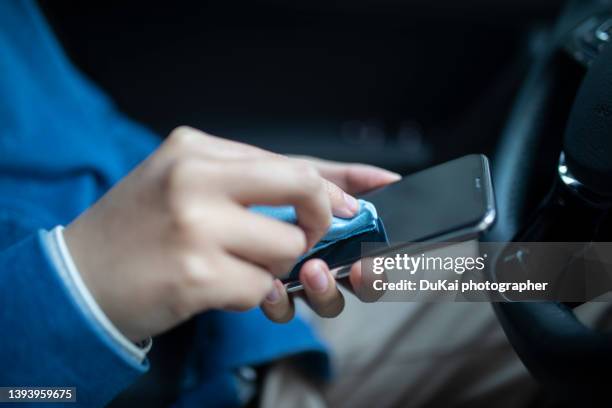 man hands cleaning the surface of a smartphone in car - antiseptic wipe stockfoto's en -beelden