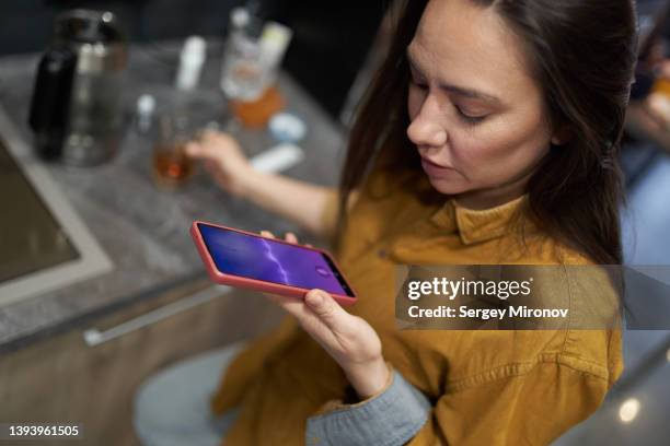 woman sending voice message in kitchen - speech recognition stockfoto's en -beelden