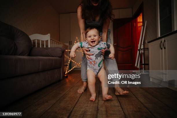 mother walking with happy baby boy on wooden floor at home - primeiros passos imagens e fotografias de stock