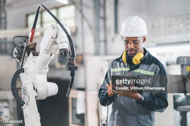 african american engineer working automatic robotic arm machine in factory. male technician worker maintenance automatic robotic hand in smart factory, industrial and manufacturing concept. - 工業用ロボット ストックフォトと画像