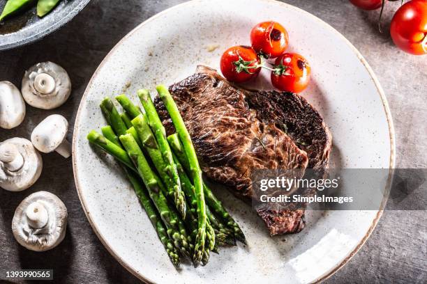 grilled rib eye steak with asparagus tomatoes and mushroom sauce. - cooked asparagus stock pictures, royalty-free photos & images