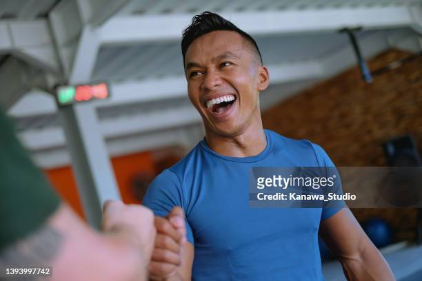 smiling indonesian athlete giving fist bump to his workout partner - fitness man gym stockfoto's en -beelden