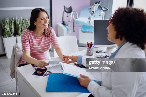 il medico incoraggia la donna incinta tenendole la mano durante la consultazione prenatale - ginecologo foto e immagini stock