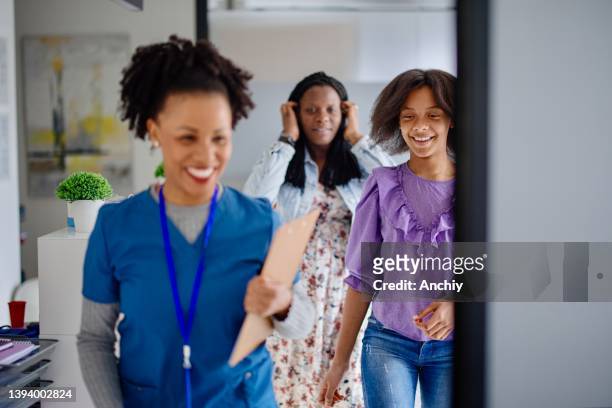 nurse accompanies teen girl entering doctors office with her mom - hpv vaccine 個照片及圖片檔