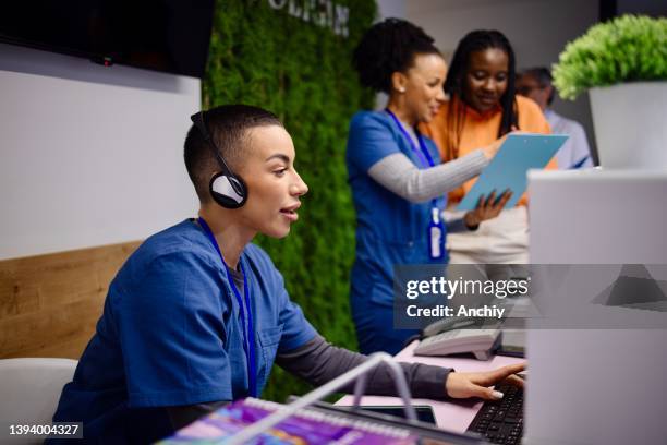 nurse talking on telephone at hospital reception - secretary stock pictures, royalty-free photos & images