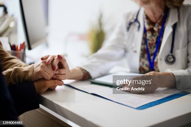 shot of an unrecognizable doctor holding hands with her patients during a consultation - cancro do ovário imagens e fotografias de stock