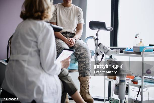 unkenntlicher soldat im gespräch mit ärztin - gynecological examination stock-fotos und bilder