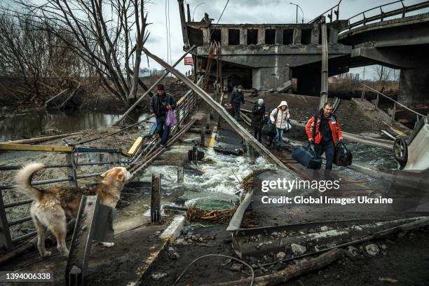 Local residents cross a makeshift walkway over a destroyed bridge during the evacuation from the city on March 05, 2022 in Irpin, Ukraine. The...