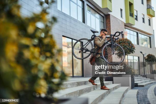 sustainably commutes to work. businessman with bicycle outdoors - carrying bike stock pictures, royalty-free photos & images