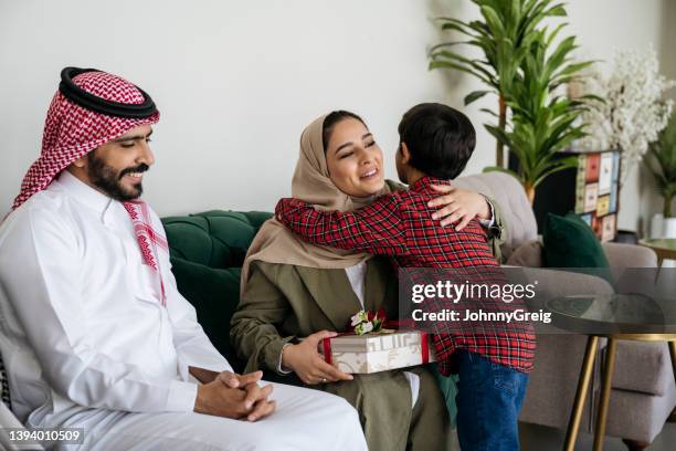 mother and son embracing during eid al-fitr gift exchange - ramadan giving stockfoto's en -beelden