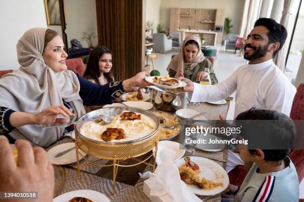 mujer saudita madura sirviendo saleeg a miembro de la familia - arab family eating fotografías e imágenes de stock