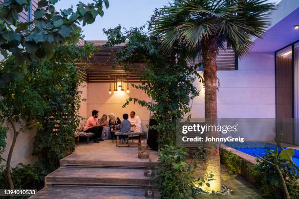 familie aus dem nahen osten, die sich in der abenddämmerung auf der außenterrasse entspannt - modern house dusk stock-fotos und bilder