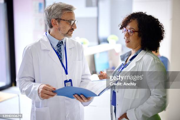 doctors standing near reception desk reading chart - endoscope stock pictures, royalty-free photos & images