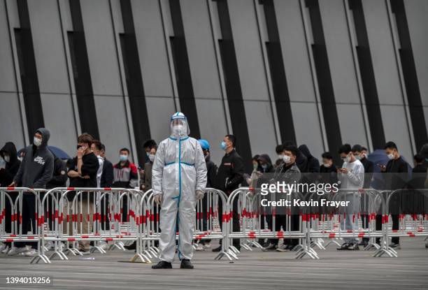 Health worker wears a protective suit as he directs people where to line up for nucleic acid tests to detect COVID-19 at a makeshift testing site in...