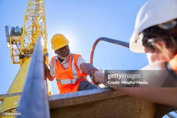 african american male cargo handler helping female coworker to getting on harbor cargo crane - longshoremen 個照片及圖片檔