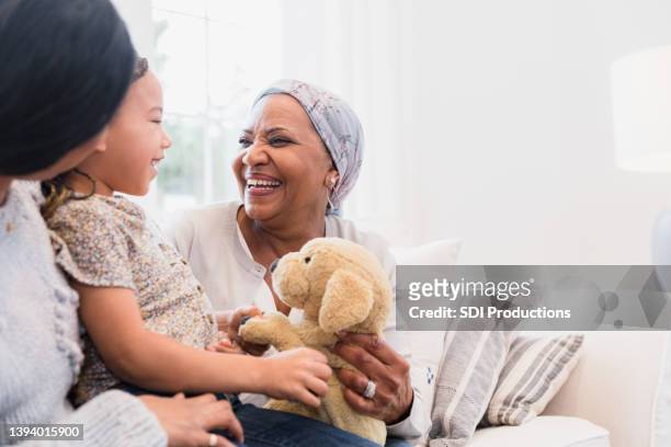 grandmother smiles while listening to her granddaughter - woman home with sick children stock pictures, royalty-free photos & images