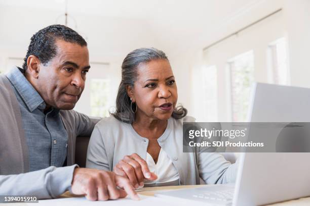 couple sit together at the computer - retirement decisions stock pictures, royalty-free photos & images
