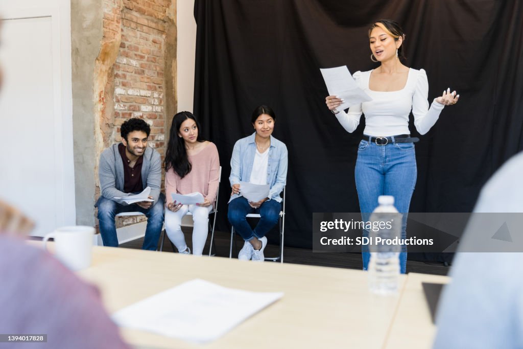 Young woman presents monologue to unrecognizable judges in foreground
