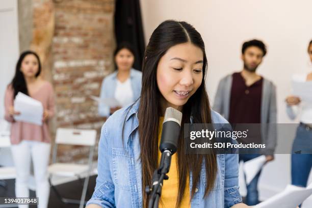 woman reads part into microphone during play practice - improv stock pictures, royalty-free photos & images