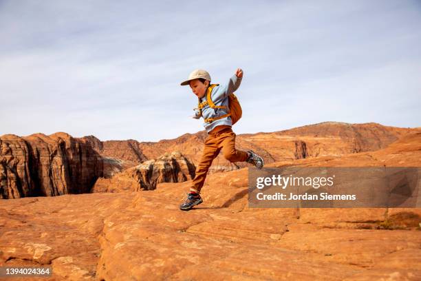 a young boy jumping off a rock while hiking. - boys camping stock-fotos und bilder