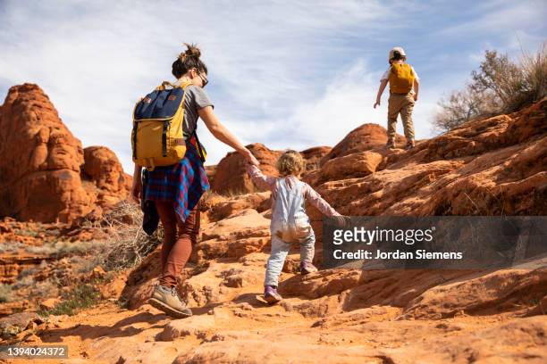 a mother and her two kids hiking a rocky trail in the desert. - utah hiking stock pictures, royalty-free photos & images