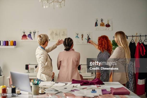 ファッションデザインに取り組む4人の女性同僚 - 繊維工業 ストックフォトと画像