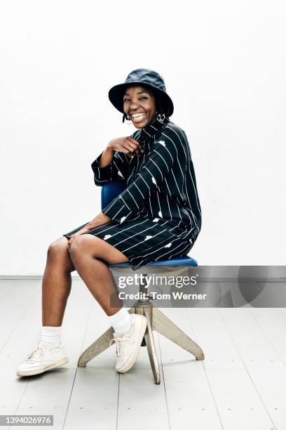 portrait of woman in striped dress sitting on stool - schwarzes kleid stock-fotos und bilder