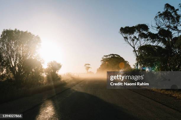 dust storm sweeping across rural road at sunset - australia heat stock pictures, royalty-free photos & images