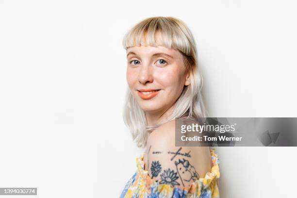 portrait of blond woman with shoulder tattoo - kopfbild stock-fotos und bilder