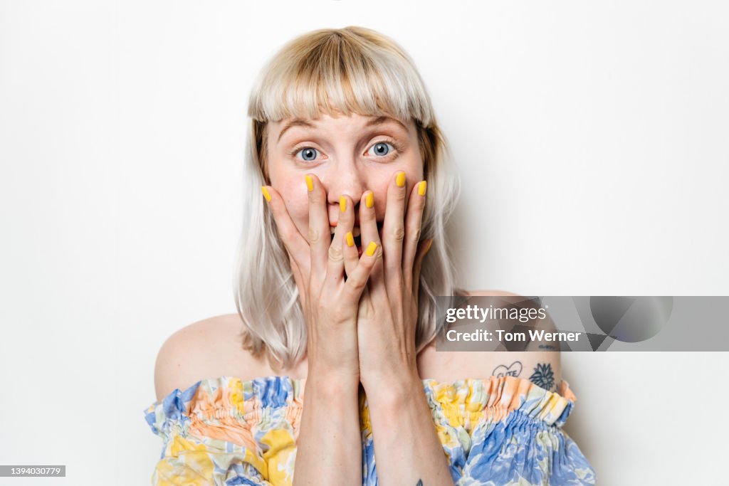 Portrait Of Excited Blond Woman With Hands Covering Mouth