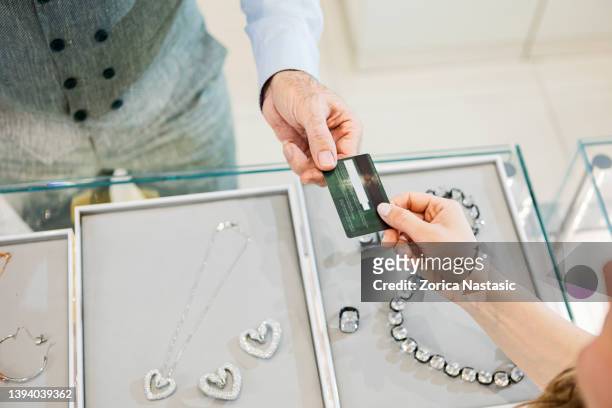 young unrecognizable woman buying at a jewelry store with credit card - diamond jeweller stock pictures, royalty-free photos & images