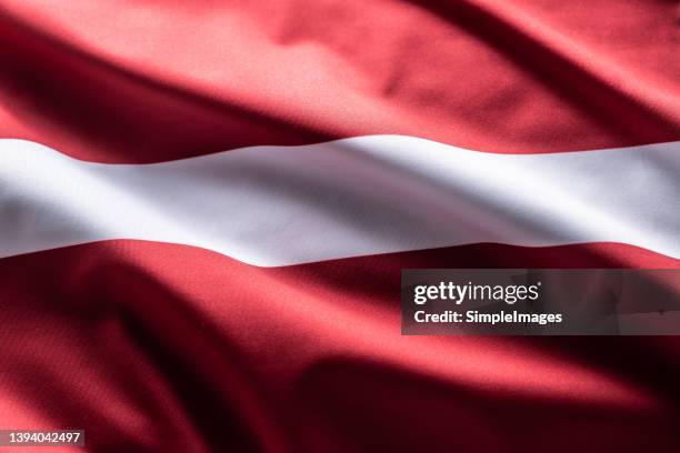 the latvian flag blows in the wind. - bandera de letonia fotografías e imágenes de stock