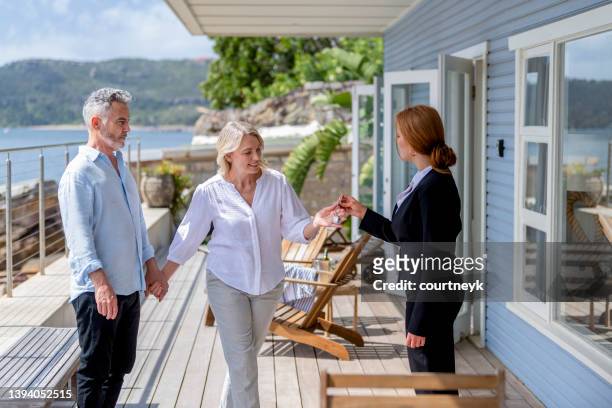 real estate agent giving a mature couple the key to their new waterfront house. - house key 個照片及圖片檔