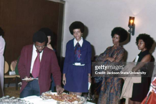 Paula Giddings standing by food counter at a party during The Phillis Wheatley Poetry Festival.