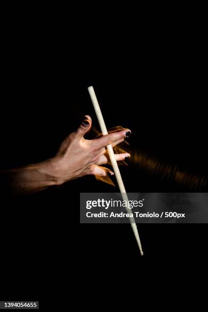 drum sticks,cropped hand holding stick against black background,argentina - 太鼓のばち ストックフォトと画像