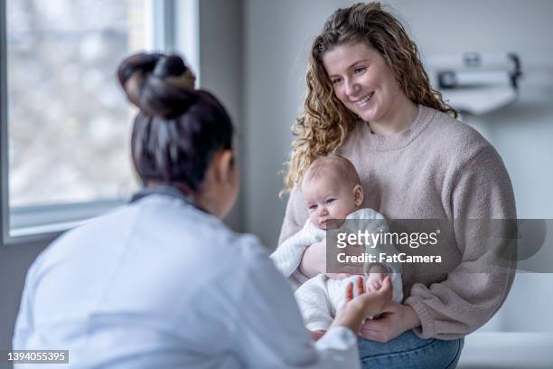 baby holding a doctors finger - doctor and baby stockfoto's en -beelden