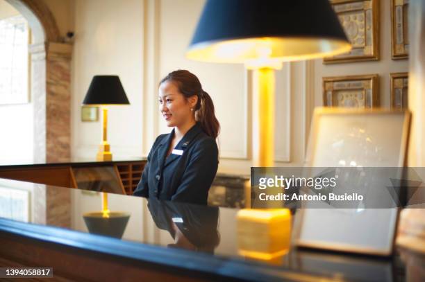 young asian woman at hotel desk - concierge stockfoto's en -beelden
