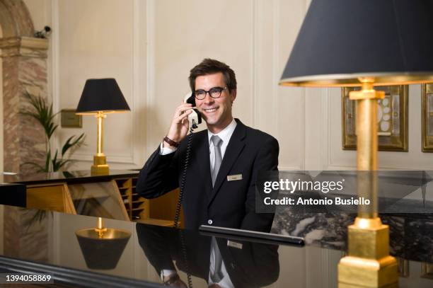 concierge talking on the phone at the hotel desk - booking hotel foto e immagini stock