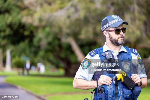 front view of police officer patrolling street of city, nsw sydney australia, background with copy sapce - new south wales police stock pictures, royalty-free photos & images