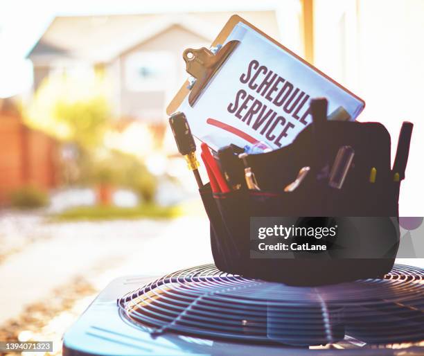 air conditioning unit with a work bag of tools on top and a reminder to schedule a service - ac repair stock pictures, royalty-free photos & images