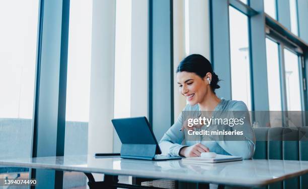 hermosa mujer con auriculares y viendo algo divertido en su tableta - color azul fotografías e imágenes de stock