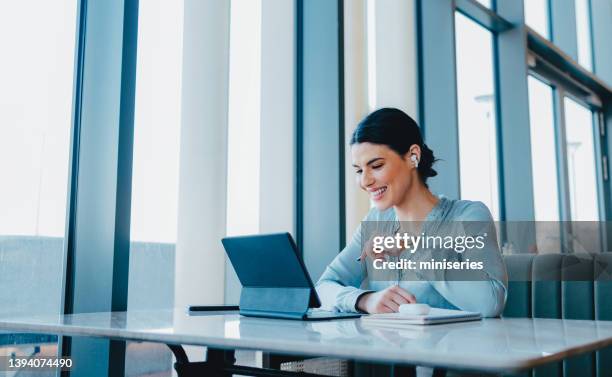 hermosa mujer con auriculares y viendo algo divertido en su tableta - remote location fotografías e imágenes de stock